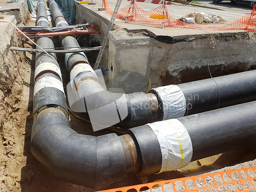 Image of Laying heating pipes in a trench at construction site.