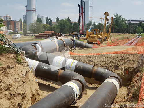 Image of Laying heating pipes in a trench at construction site.