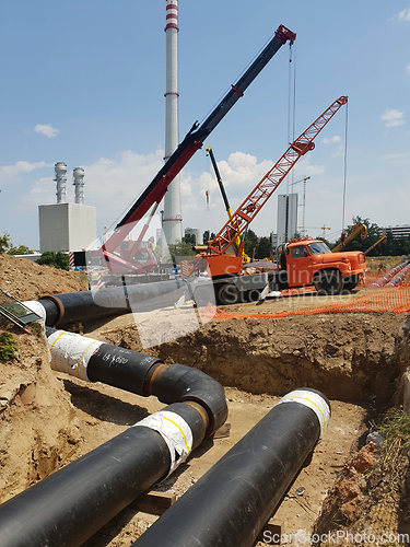 Image of Laying heating pipes in a trench at construction site.