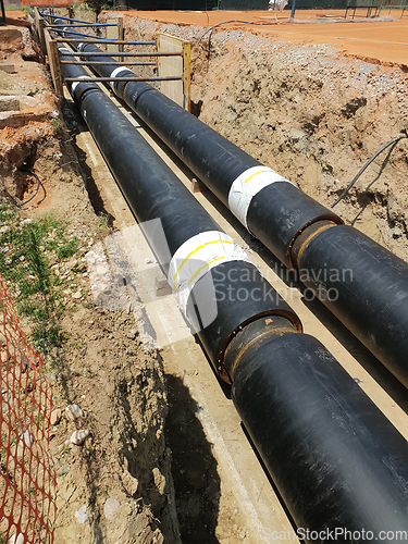 Image of Laying heating pipes in a trench at construction site.