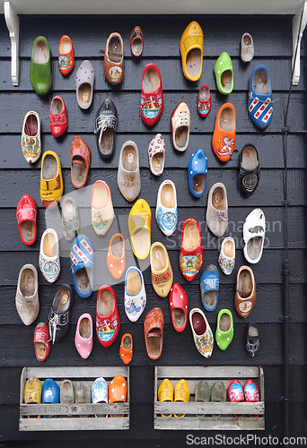 Image of Many multicolored vintage Dutch Klomp shoes on black wood panel 