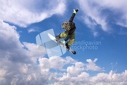 Image of Snowboarder in action jumping against blue sky