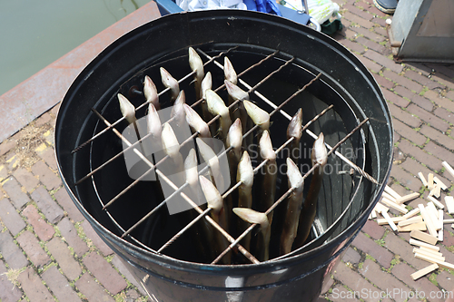 Image of Traditional smoked eels, fish in a smoking in metal barrel
