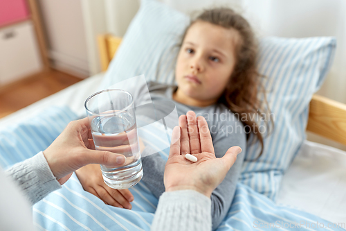 Image of mother giving medicine to sick little daughter