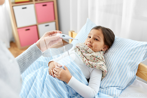 Image of mother measuring temperature of sick daughter