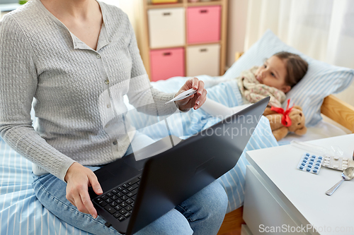 Image of mother measuring temperature of sick daughter