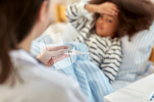 Image of doctor measuring sick girl's temperature