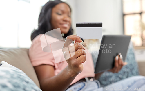 Image of happy woman with tablet pc and credit card at home