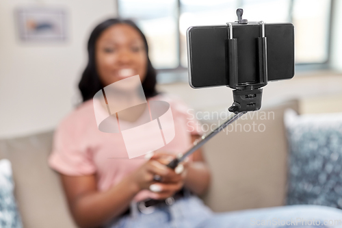 Image of happy african american woman taking selfie at home