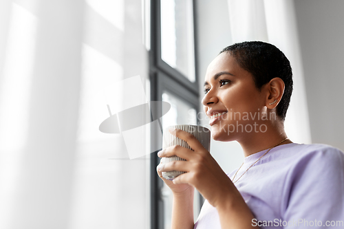 Image of happy woman with coffee looking out of window