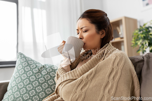 Image of sick asian woman drinking hot tea at home