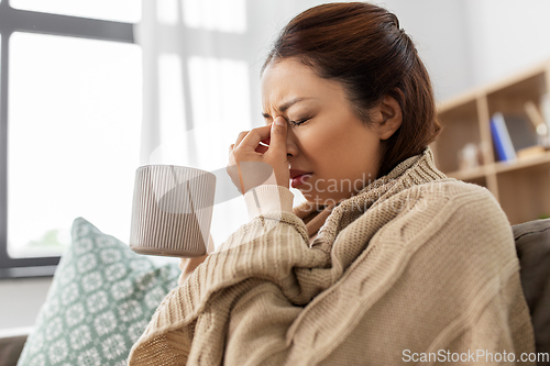 Image of sick asian woman drinking hot tea at home