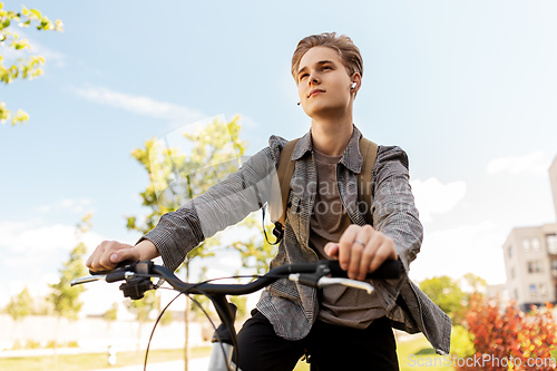 Image of teenage boy with earphones and bag riding bicycle