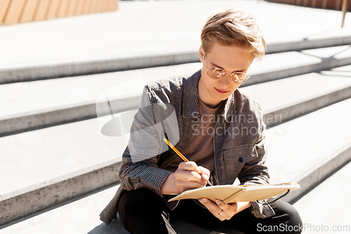 Image of young man with notebook or sketchbook in city