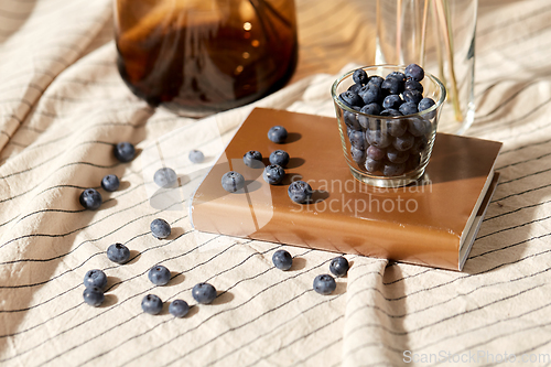 Image of cup of blueberry, book and dried flowers in vases