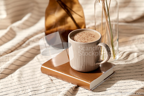 Image of cup of coffee on book and dried flowers in vases