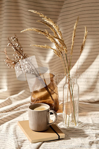 Image of cup of coffee, diary and dried flowers in vases