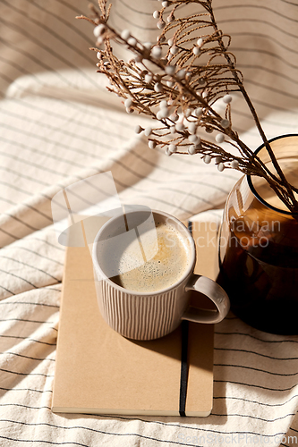 Image of cup of coffee, diary and dried flowers in vases