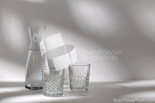 Image of two glasses and jug with water on white background