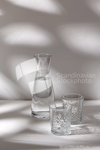 Image of two glasses and jug with water on white background