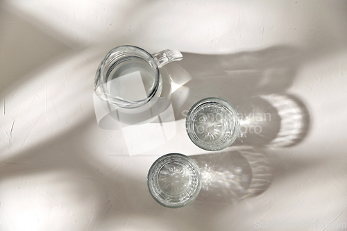 Image of two glasses and jug with water on white background