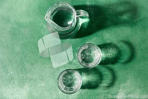 Image of two glasses and jug with water on green background