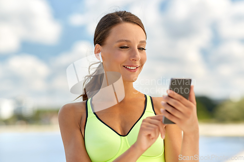 Image of woman with earphones and smartphone doing sports