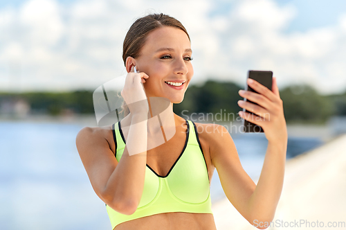 Image of woman with earphones and smartphone doing sports