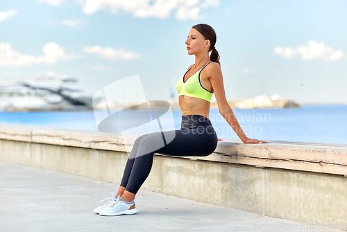 Image of happy young woman doing sports on sea promenade