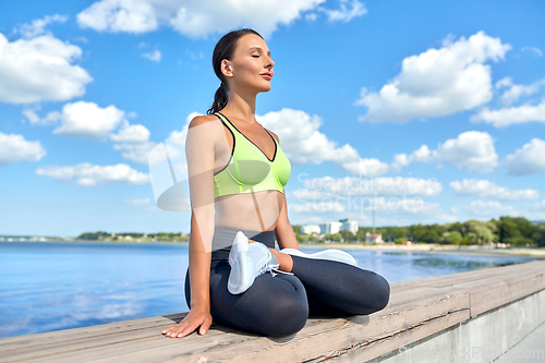 Image of young woman meditating in lotus pose at seaside