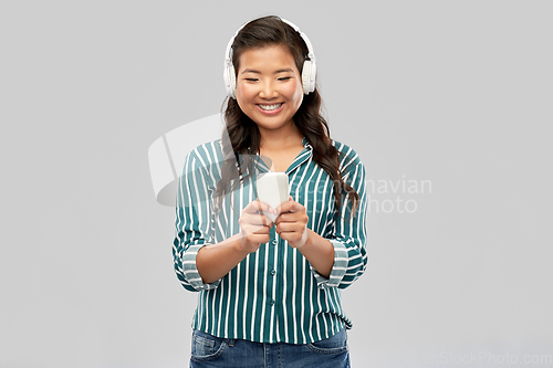 Image of happy asian woman in headphones listening to music