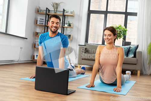 Image of happy couple with laptop exercising at home