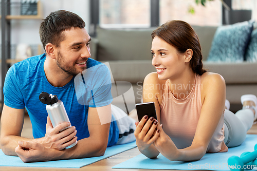 Image of happy couple with smartphone after sports at home