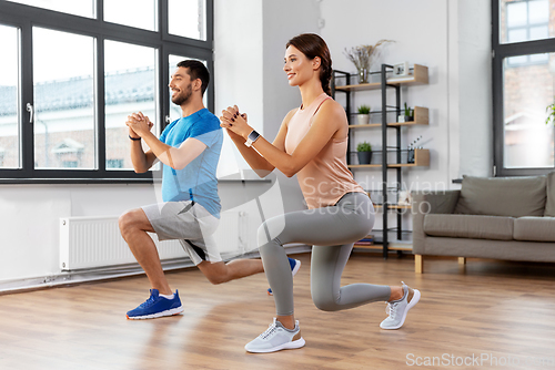 Image of happy couple exercising and doing squats at home