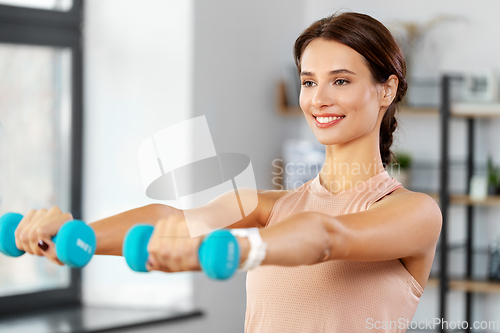 Image of happy woman with dumbbells exercising at home