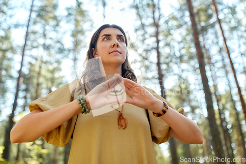 Image of woman or witch performing magic ritual in forest