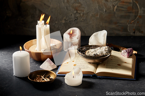 Image of magic book, sage, burning candles and ritual staff