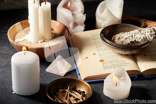 Image of magic book, sage, burning candles and ritual staff