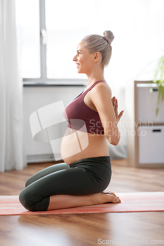 Image of happy pregnant woman doing yoga at home