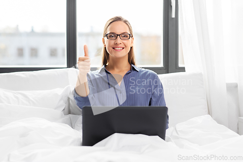 Image of young woman with laptop in bed at home bedroom