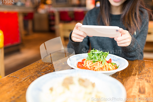 Image of Woman taking photo on dish in coffee shop