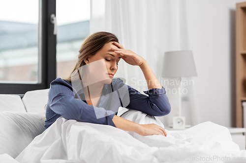 Image of sleepy woman sitting in bed at home