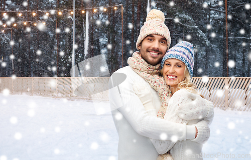 Image of happy couple hugging on outdoor ice skating rink