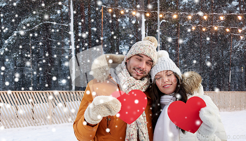 Image of happy couple with red hearts at ice rink in winter