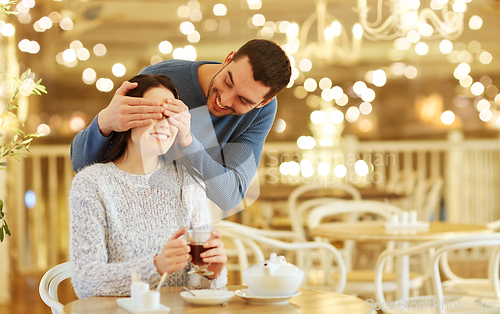 Image of happy couple drinking tea at cafe over lights