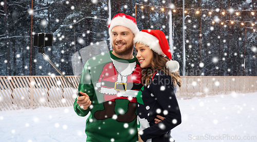 Image of happy couple in christmas sweaters taking selfie