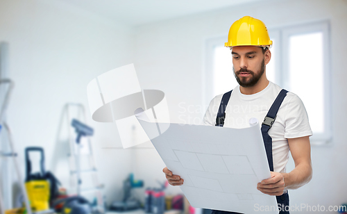 Image of male worker or builder in helmet with blueprint