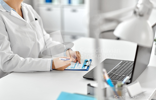 Image of doctor with laptop and medical report at hospital