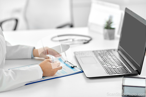 Image of doctor with laptop and medical report at hospital