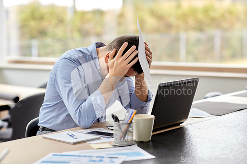 Image of stressed man with laptop working at home office